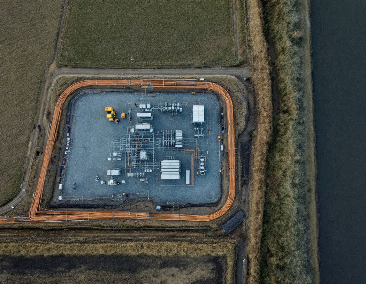 Luchtfoto van een hoogspanningsstation met kabelmantelbuizen in de polder